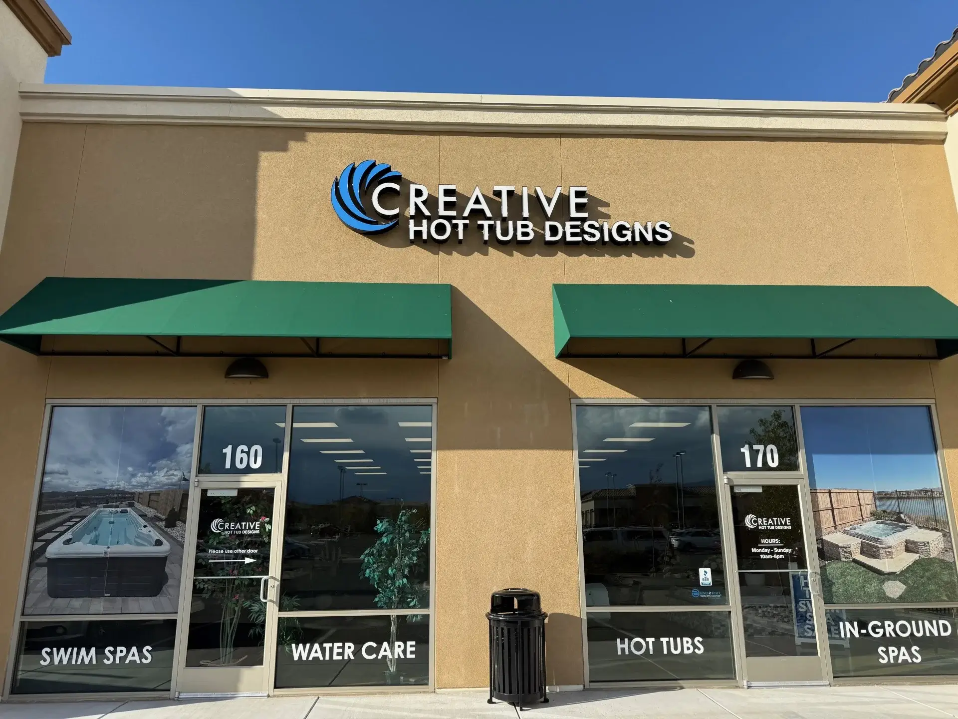 Creative Hot Tub Designs showroom exterior in Reno, NV, featuring storefronts labeled 'Swim Spas' and 'Hot Tubs,' with green awnings and promotional images on glass doors.