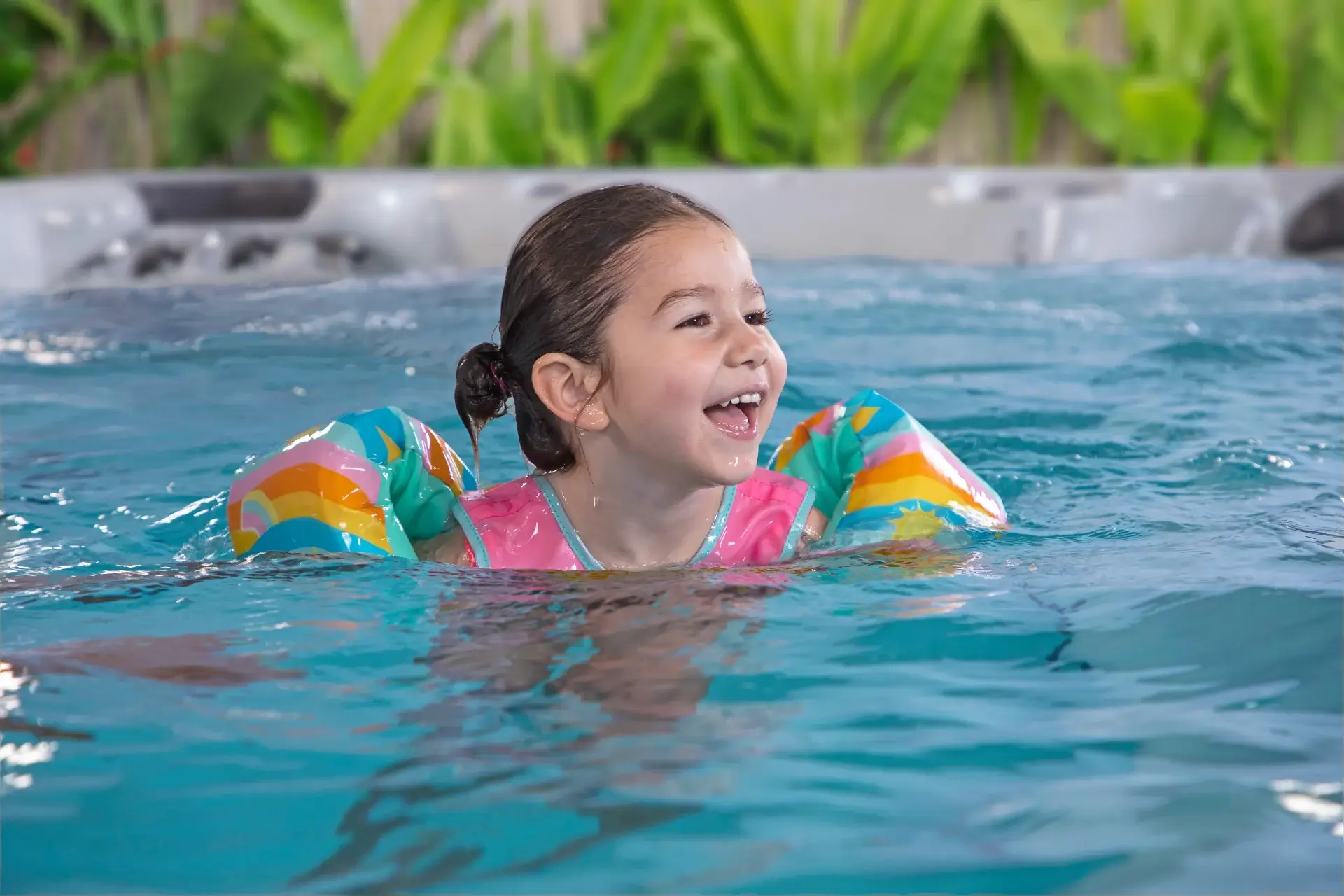 Girl smiling and enjoying swimming in a colorful swim spa, highlighting family fun and relaxation, associated with Creative Hot Tub Designs in Reno, NV.