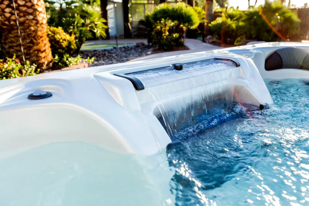 Hot tub water feature with cascading waterfall and hydrotherapy jets, surrounded by lush landscaping, promoting relaxation and wellness, from Creative Hot Tub Designs in Reno NV and Sparks NV.