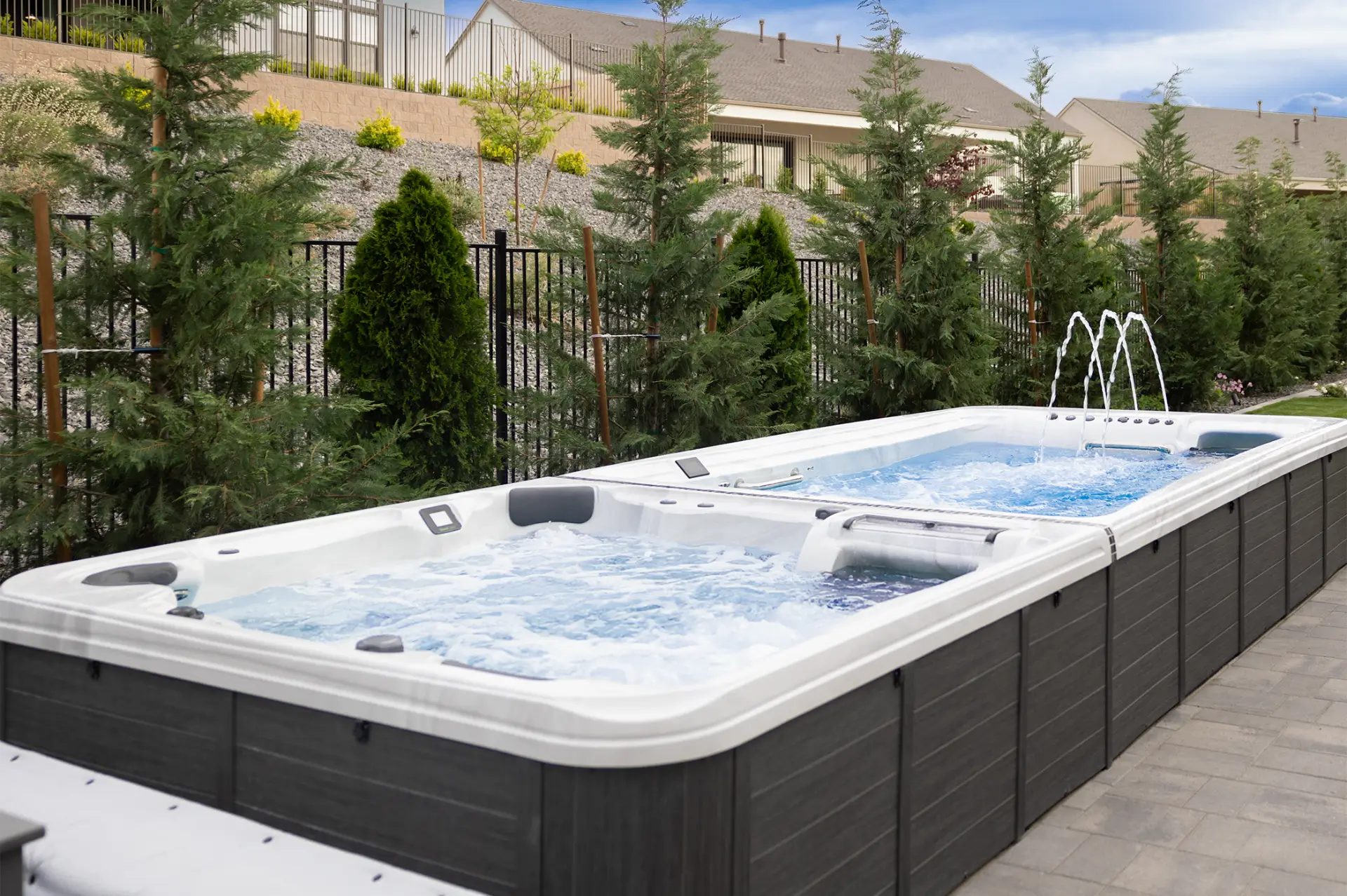 Swim spa with adjustable current and hydrotherapy features, surrounded by greenery and fencing, showcasing a modern backyard installation for wellness and relaxation.
