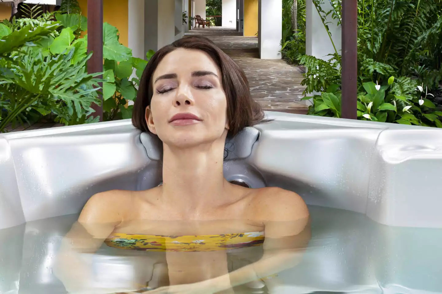 Woman relaxing in a hot tub, surrounded by lush greenery, illustrating the therapeutic benefits of hydrotherapy from Creative Hot Tub Designs in Reno NV and Sparks NV.