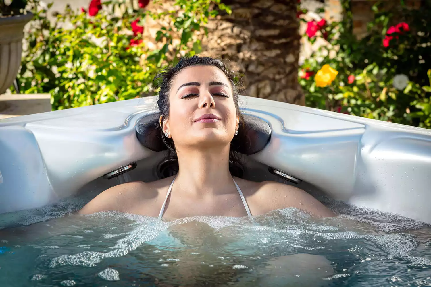 Woman relaxing in hot tub, enjoying hydrotherapy benefits, surrounded by vibrant flowers, promoting wellness and stress relief, Creative Hot Tub Designs, Reno NV, Sparks NV.
