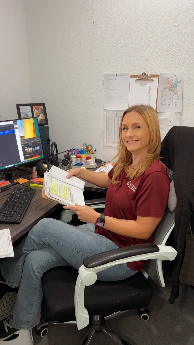 Ally, Water Care Coordinator at Creative Hot Tub Designs, smiling while reviewing notes in her office in Sparks, NV, with a computer and organized workspace.